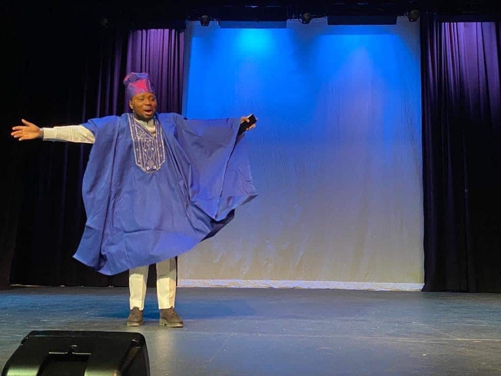 Soro Soke: a performer in a blue agbada, arms outstretched
